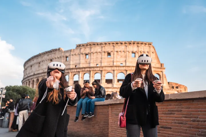 Two people with VR headsets near the Colosseum, holding controllers.